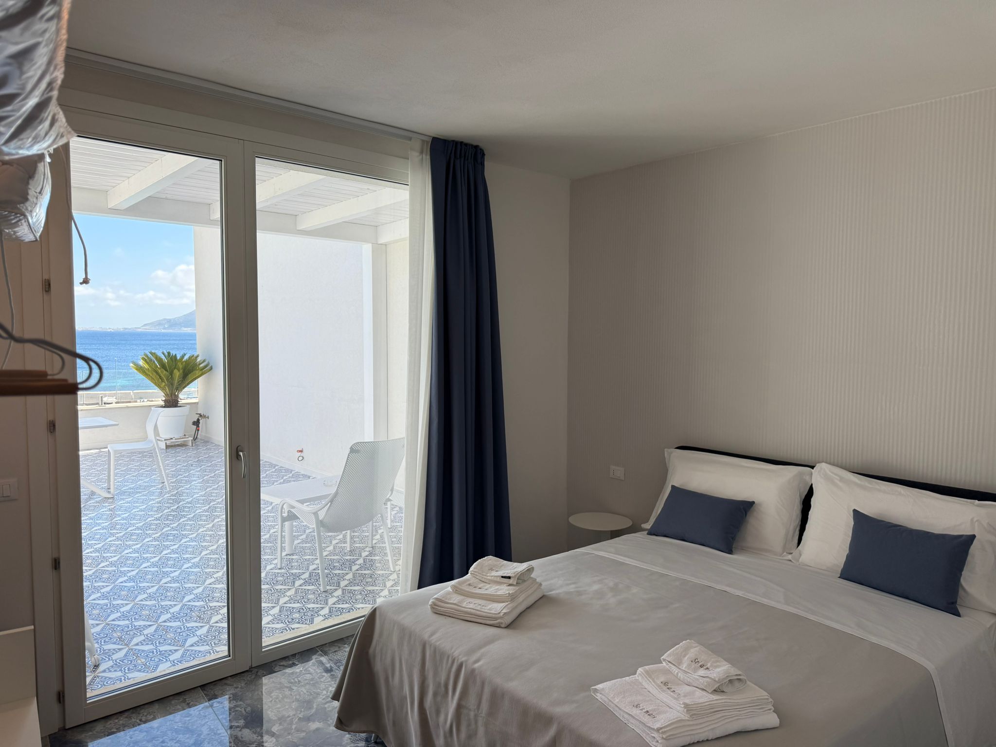 Suite Blue Moon — letto con cuscini blu navy e vista mare