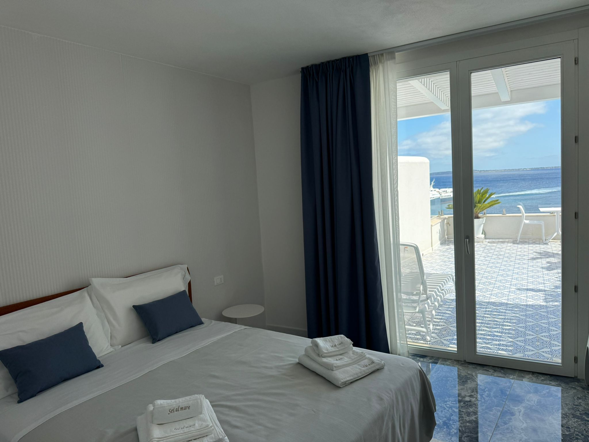 Suite Blue Orange — camera con cuscini blu e porta-finestra sulla terrazza