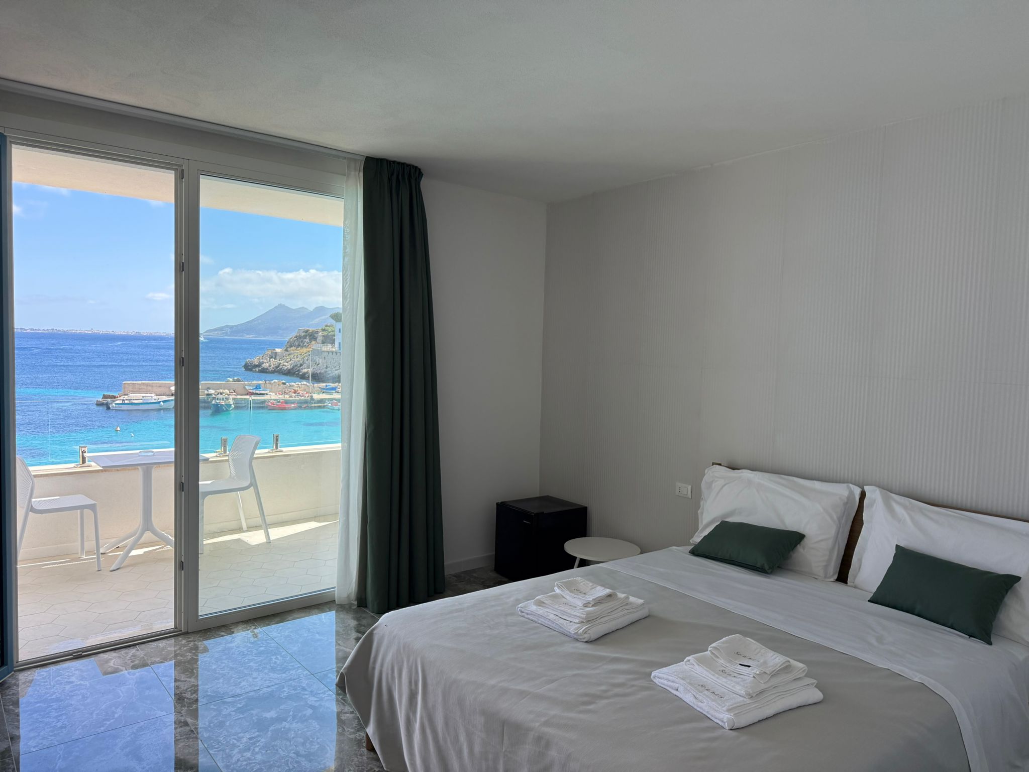 Suite Jade — letto con cuscini jade e porta-finestra sul mare